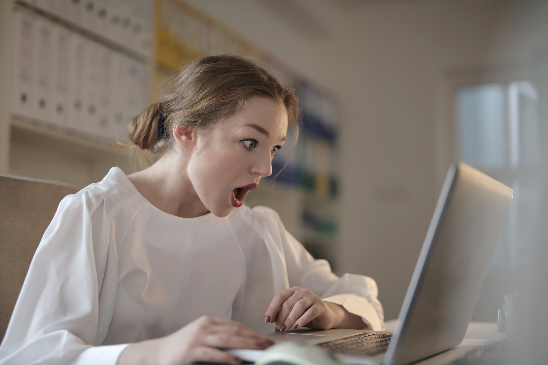 Женщина в шоке смотрит на ноутбук